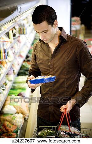 Stock Photo - Man reading the label on food packaging in a supermarket. Fotosearch
