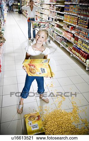 Stock Image - Naughty young girl emptying cereal over a supermarket floor. Fotosearch