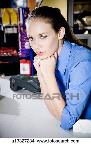 Picture - Portrait of a bored supermarket checkout assistant. Fotosearch