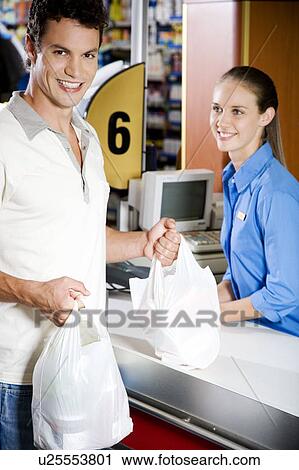 Stock Image - Portrait of a customer and supermarket checkout assistant. Fotosearch