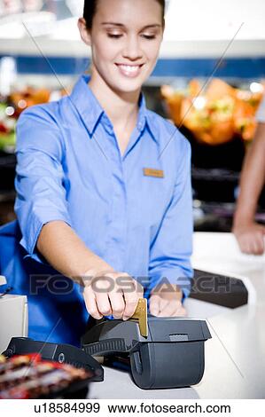 Portrait of a supermarket checkout assistant using a credit card machine View Large Photo Image Stock Photo - Portrait of a supermarket checkout assistant using a credit card machine . Fotosearch