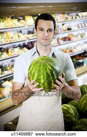 Portrait of a supermarket shop assistant holding a watermelon View Large Photo Image Stock Photo - Portrait of a supermarket shop assistant holding a watermelon. Fotosearch