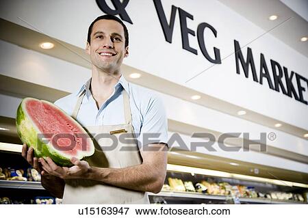 Portrait of a supermarket shop assistant holding a watermelon View Large Photo Image Stock Photo - Portrait of a supermarket shop assistant holding a watermelon. Fotosearch