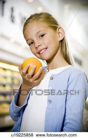 Stock Photo - Portrait of a young girl holding a grapefruit in a supermarket. Fotosearch