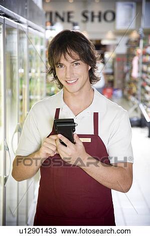 Stock Image - Shop assistant stocktaking in a supermarket. Fotosearch
