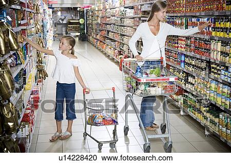 Woman and a young girl with a shopping trolley walking down a supermarket aisle View Large Photo Image Stock Image - Woman and a young girl with a shopping trolley walking down a supermarket aisle. Fotosearch