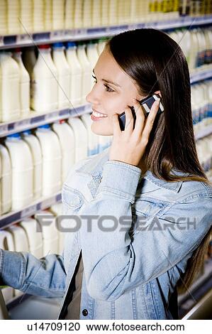 Woman on her mobile phone at a supermarket View Large Photo Image Stock Image - Woman on her mobile phone at a supermarket. Fotosearch