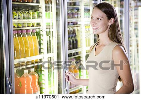 Woman opening a refrigerator door in a supermarket View Large Photo Image Stock Image - Woman opening a refrigerator door in a supermarket. Fotosearch