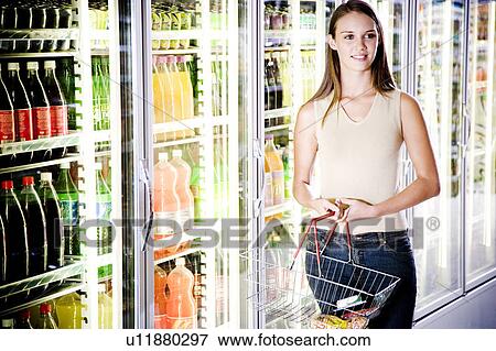Stock Photo - Woman stood next to a refrigerator door in a supermarket. Fotosearch