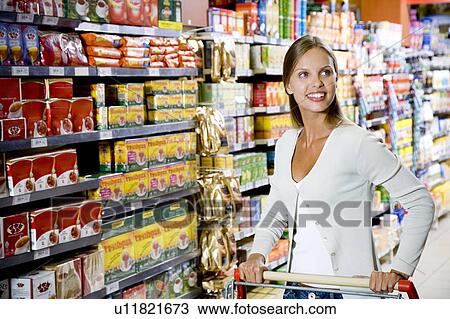 Woman with a trolley walking down a supermarket aisle View Large Photo Image Stock Image - Woman with a trolley walking down a supermarket aisle. Fotosearch