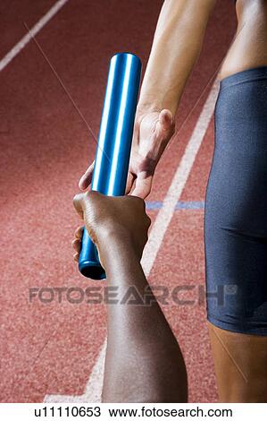 Stock Image - Baton passing between relay runners. Fotosearch