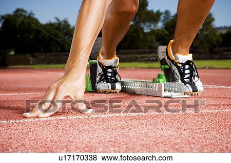 Stock Photo - Female athlete in the starting blocks. Fotosearch