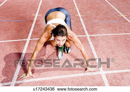 Stock Photograph - Female athlete in the starting blocks. Fotosearch