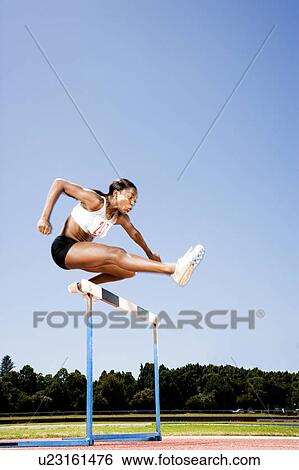 Female hurdler in action View Large Photo Image Stock Photograph - Female hurdler in action. Fotosearch