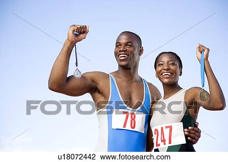 Stock Image - Portrait of a female and athletes with their medals. Fotosearch