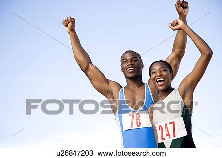 Stock Image - Portrait of a female and athletes with their arms in the air. Fotosearch