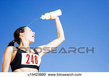 Stock Photo - Portrait of a female athlete drinking form a water bottle. Fotosearch