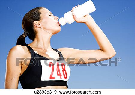 Portrait of a female athlete drinking form a water bottle View Large Photo Image Stock Photo - Portrait of a female athlete drinking form a water bottle. Fotosearch