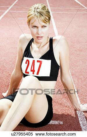 Stock Photography - Portrait of a female athlete resting and sitting on the running track. Fotosearch