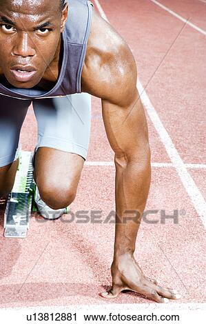Stock Image - Portrait of a male athlete in the starting blocks. Fotosearch