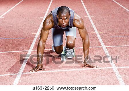 Stock Image - Portrait of a male athlete in the starting blocks. Fotosearch