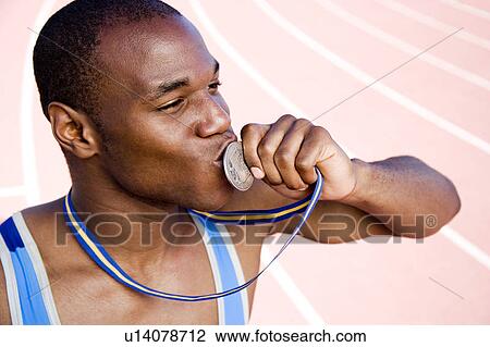 Portrait of male athlete kissing his medal View Large Photo Image Stock Image - Portrait of male athlete kissing his medal. Fotosearch