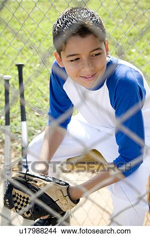 Picture - Boy in baseball gear sitting on a bench. Fotosearch