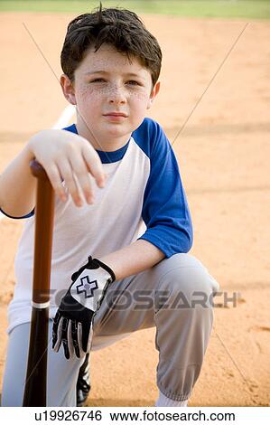Stock Photograph - Boy with baseball bat kneeling on ground. Fotosearch