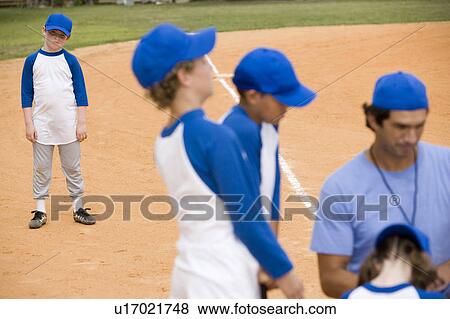 Stock Photo - Little league baseball team and coach on pitch. Fotosearch