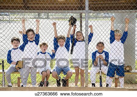 Stock Photograph - Little league baseball team cheering behind wire fence. Fotosearch