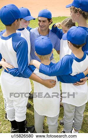 Stock Image - Little league baseball team in huddle with their coach. Fotosearch