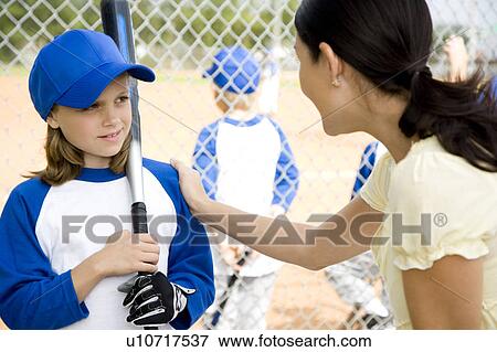 Stock Photo - Mother encouraging daughter at little league baseball game. Fotosearch
