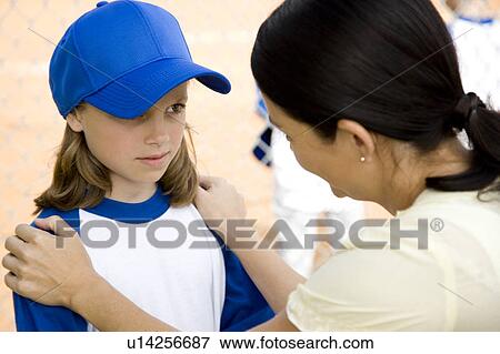 Stock Photo - Mother encouraging daughter at little league baseball game. Fotosearch