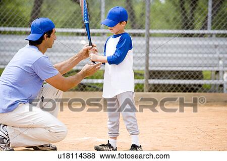 Stock Photo - Young boy being shown how to bat in baseball. Fotosearch