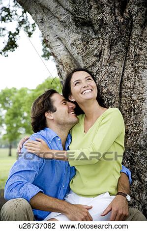 couple embracing in front of tree View Large Photo Image Stock Image - couple embracing in front of tree. Fotosearch