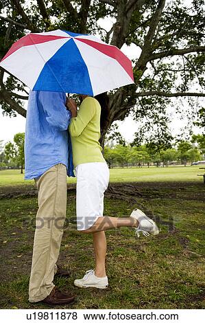 couple kissing behind umbrella View Large Photo Image Stock Photo - couple kissing behind umbrella. Fotosearch