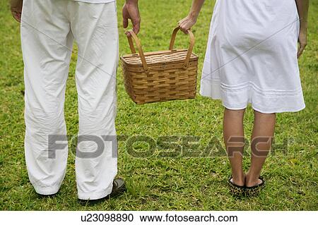 Stock Image - cropped image couple walking with picnic basket. Fotosearch