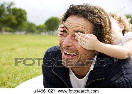 Stock Photo - father and child playing guess who in the park. Fotosearch