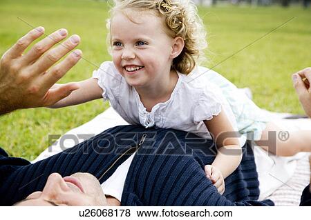 Stock Photo - Father and daughter play fighting on the grass. Fotosearch