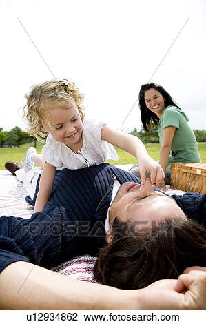 Stock Image - father and daughter playing on picnic rug. Fotosearch