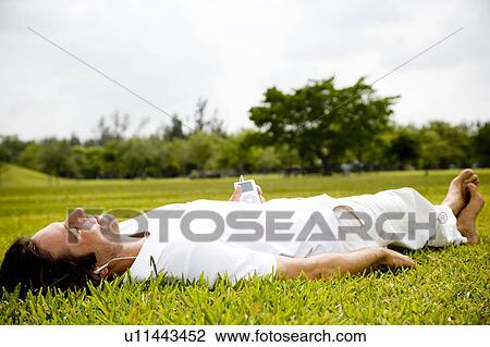 man lying on the grass relaxing View Large Photo Image Stock Image - man lying on the grass relaxing. Fotosearch