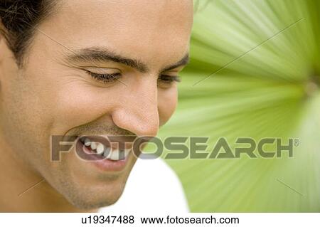 Stock Photo - Portrait of a smiling adult man in a tropical garden. . Fotosearch