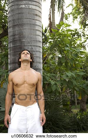 Portrait of a toned muscular man standing in a garden wearing white linen trousers View Large Photo Image Stock Image - Portrait of a toned muscular man standing in a garden wearing white linen trousers. Fotosearch