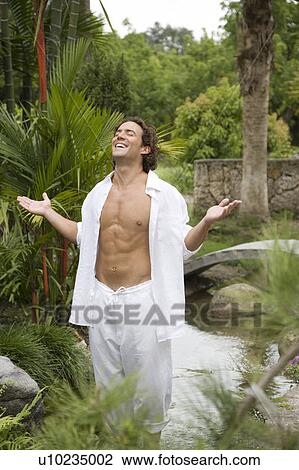 Portrait of an adult man standing in a tropical garden, arms outstretched. View Large Photo Image Stock Image - Portrait of an adult man standing in a tropical garden, arms outstretched. . Fotosearch
