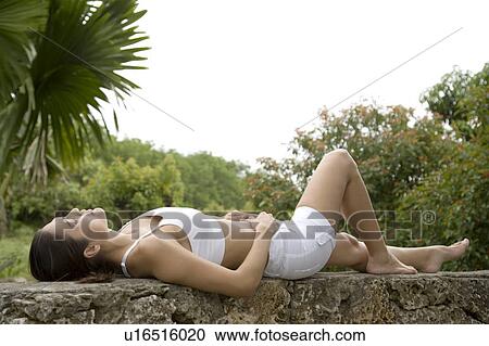 Stock Image - Portrait of an Hispanic woman laying on a wall relaxing.. Fotosearch