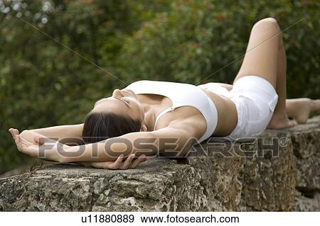 Stock Photo - Portrait of an Hispanic woman laying on a wall relaxing.. Fotosearch