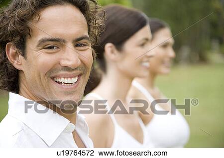 Portrait of three adults standing in a row, with man smiling View Large Photo Image Stock Image - Portrait of three adults standing in a row, with man smiling. Fotosearch