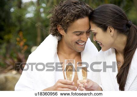 Smiling couple celebrating with champagne in a tropical garden View Large Photo Image Stock Photograph - Smiling couple celebrating with champagne in a tropical garden. Fotosearch