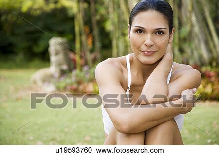 Stock Image - Smiling Hispanic woman sitting in a tropical garden. Fotosearch