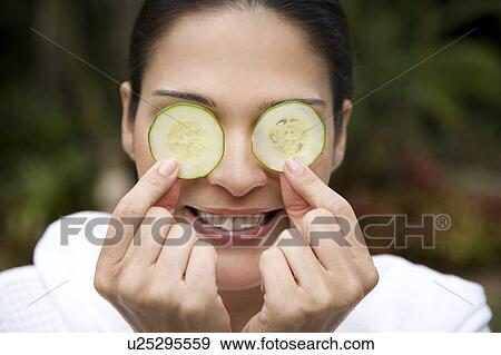 Smiling woman in a white robe with cucumbers over her eyes View Large Photo Image Stock Photo - Smiling woman in a white robe with cucumbers over her eyes. Fotosearch